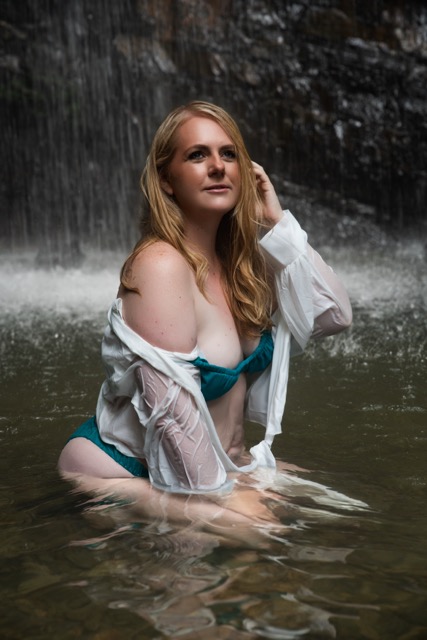 Boudoir portrait of a woman in a wet white shirt beneath a waterfall in El Yunque, Puerto Rico